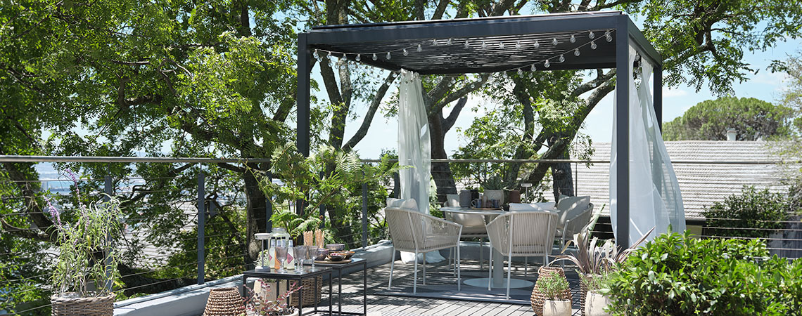 Pergola en métal avec toit, décorée de voilages et de guirlandes lumineuses sur un patio
