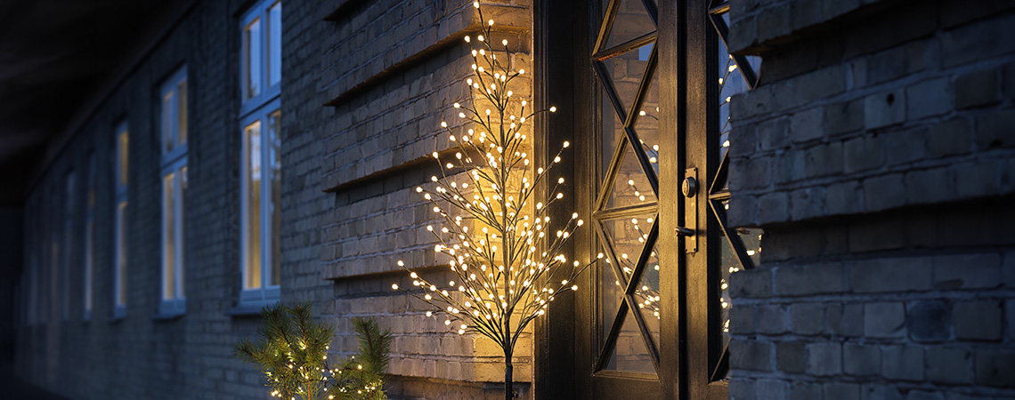 Les lumières d’intérieur et d’extérieur sont parfaites pour créer une ambiance chaleureuse en hiver. Éclairage extérieur de fête, tel qu'un sapin lumineux à LED devant la porte d'entrée d'une maison
