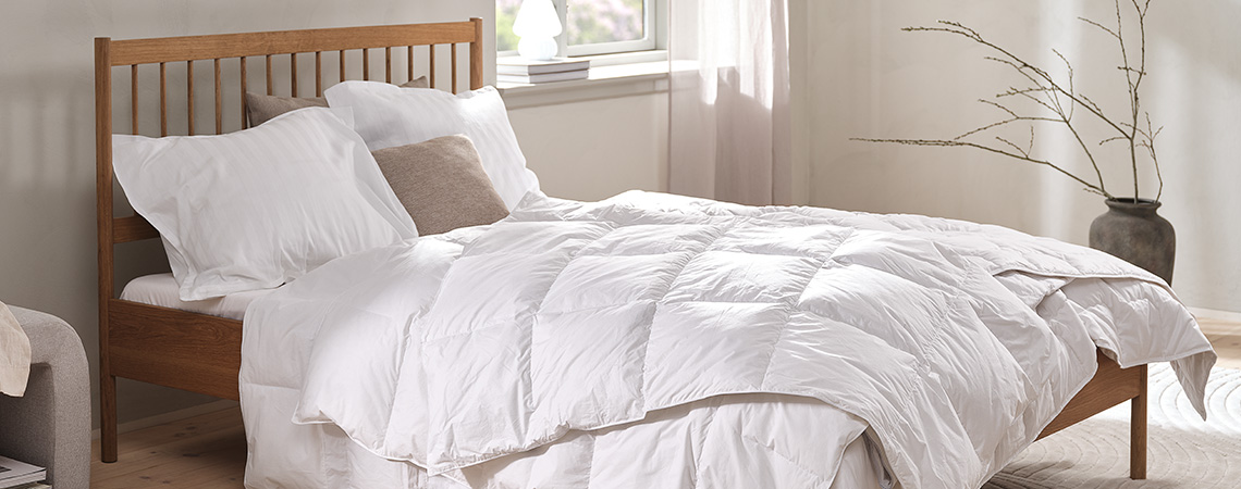 En savoir plus sur OEKO-TEX® et notre gamme de produits textiles Couette blanche sans housse et oreillers dans des taies d’oreillers blanches sur un lit dans une chambre