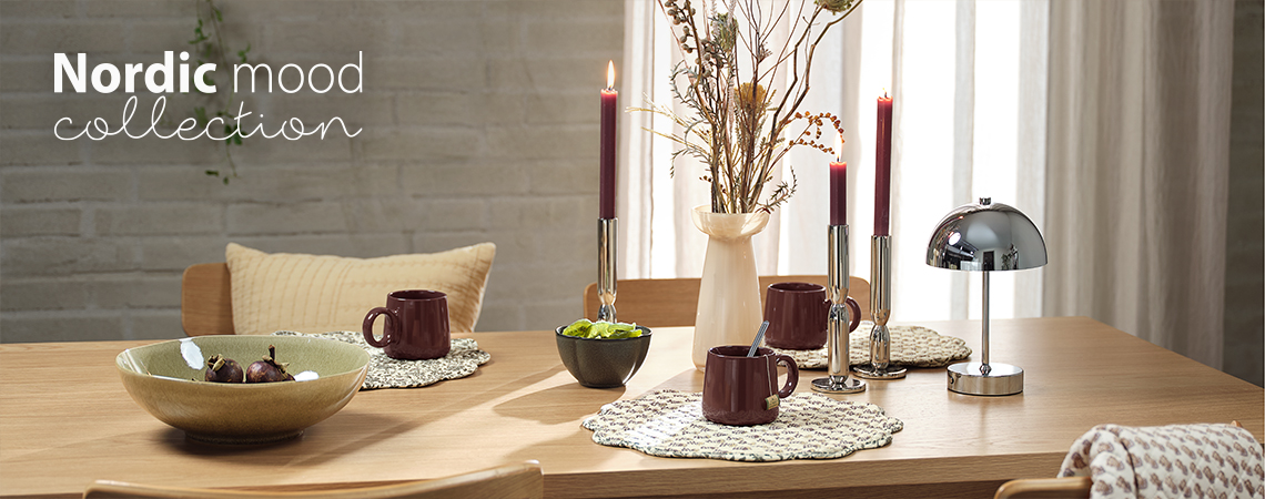 Table à manger avec bols, tasses, sets de table, vase, chandeliers et lampe à piles.