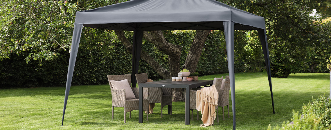 Tonnelle grise dans un jardin avec mobilier de jardin