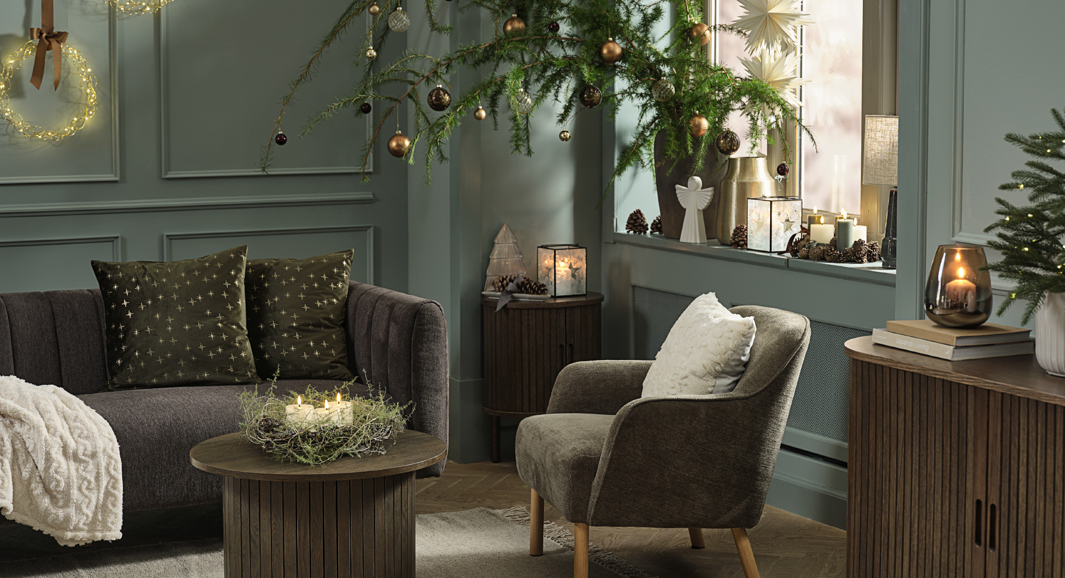 Coussins décoratifs ALVALDE et NJORD, buffet LYNGVIG et couronne de Noël SNE Salon dans les tons verts décoré pour Noël