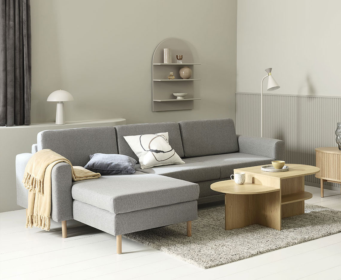 SVALBARD chaise lounge sofa Grey chaise lounge sofa in a living room with coffee table, lamps, and home decorations