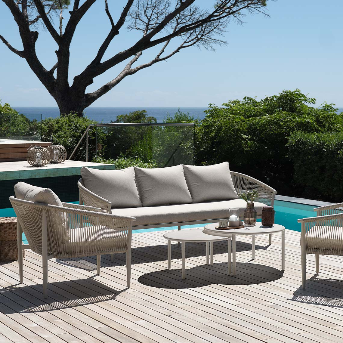 Salon d'extérieur beige clair, sans entretien, installé sur la terrasse près de la piscine 