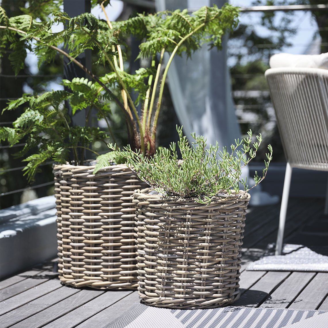 Paniers pour plantes SEGLA Deux paniers pour plantes en rotin naturel non traité sur un balcon avec des plantes