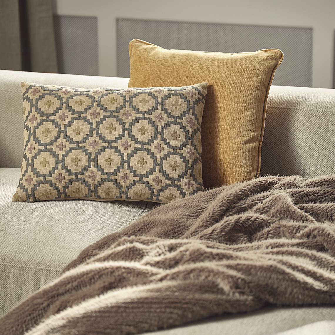 Coussin jaune HORNFIOL et à motifs BANKSIA, plaid en fausse fourrure VINTEREIK Canapé avec coussins jaunes et à motifs et un plaid