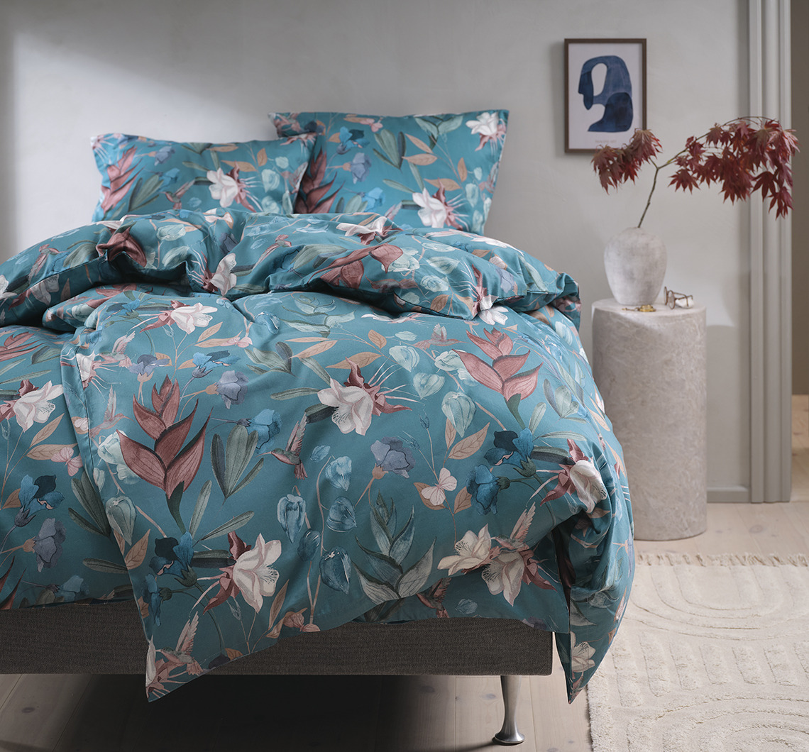 La parure de lit BERTHA présente de grands motifs floraux sur un fond bleu pétrole. Parure de lit fleurie dans une chambre