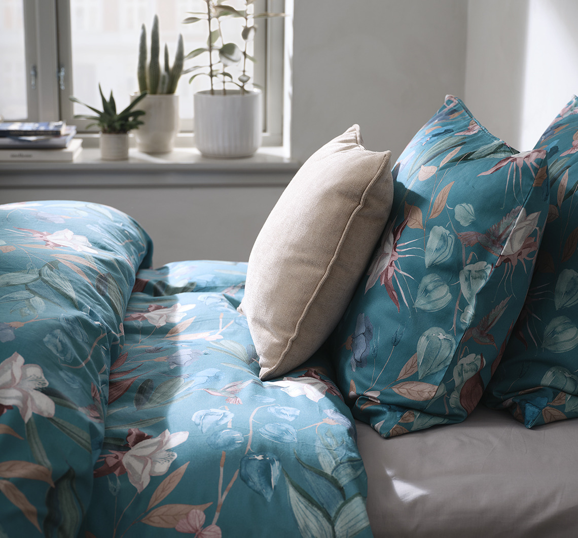 Associez BERTHA à des éléments monochromes contrastants pour un look dynamique. Chambre avec parure de lit fleurie et coussin supplémentaire de couleur contrastante
