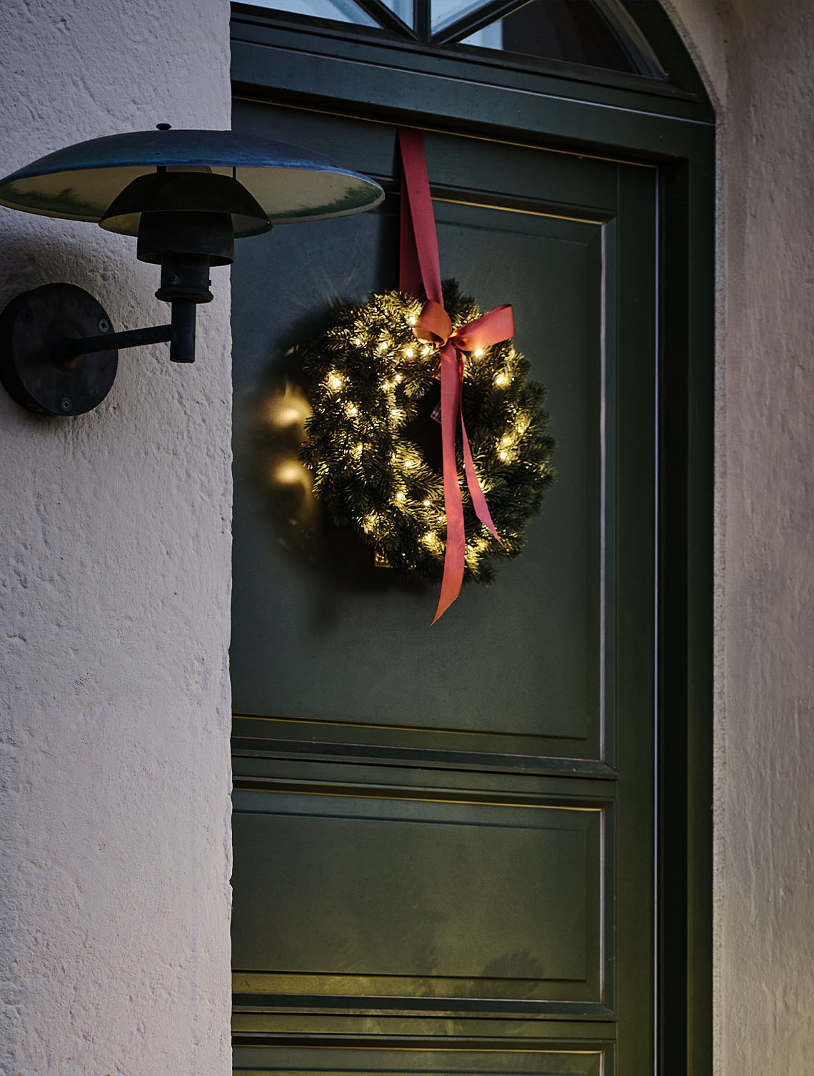 FENRIS wreath with built-in timer Couronne de fête d'extérieur illuminée de petites lumières, accrochée à une porte.