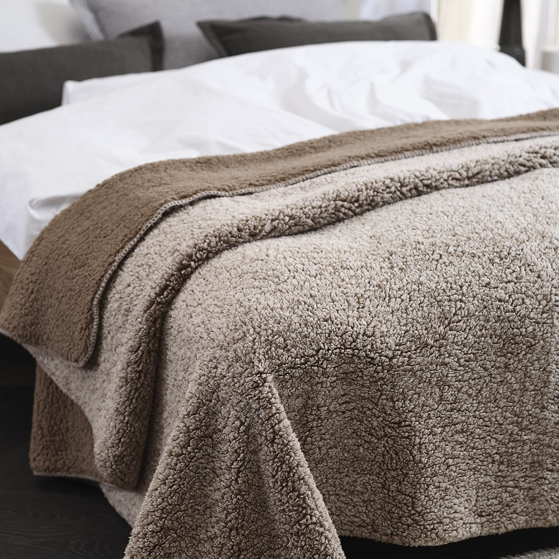 Plaid marron en polaire sur un lit dans une chambre