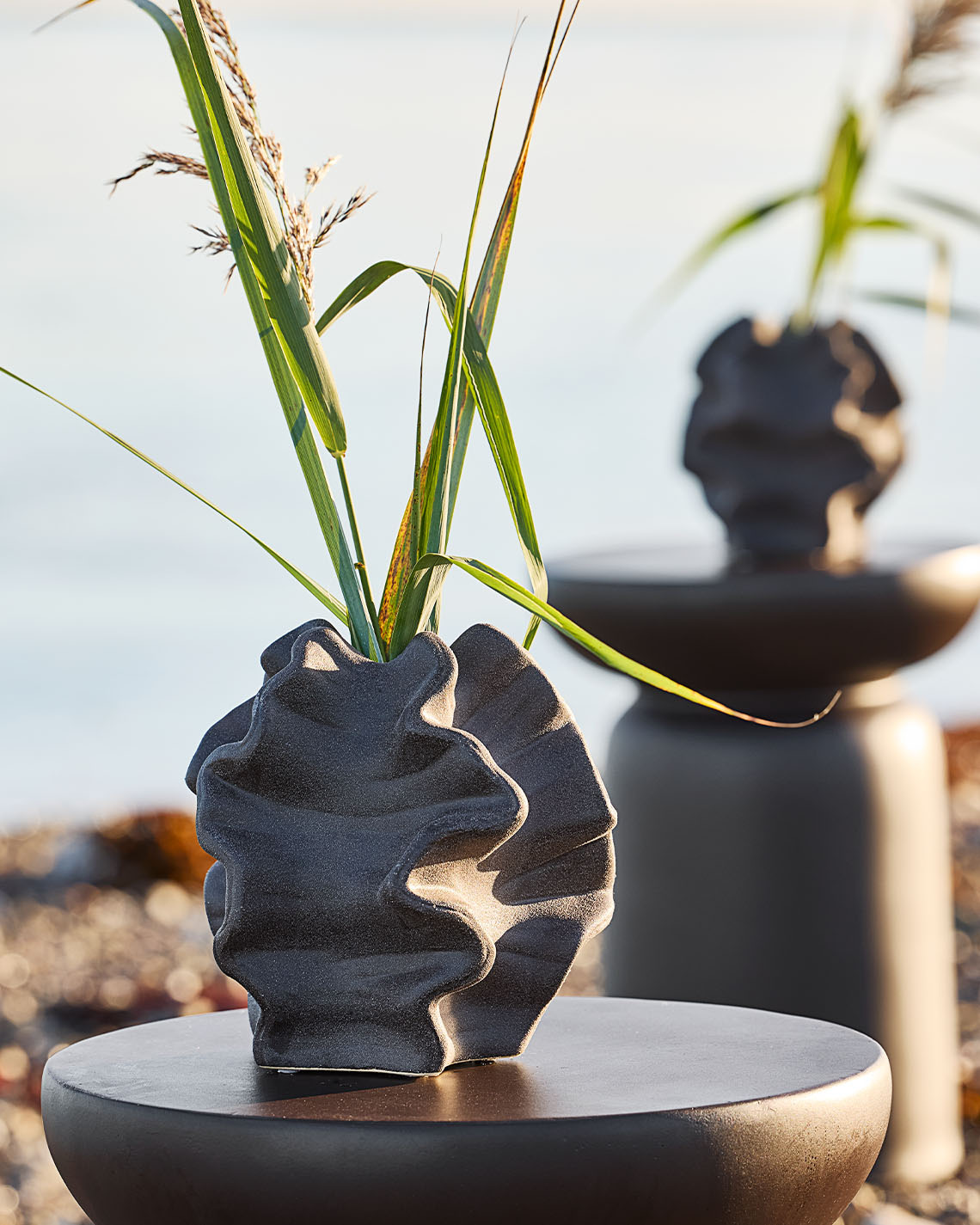 Vase de forme organique sur piédestal sur une plage