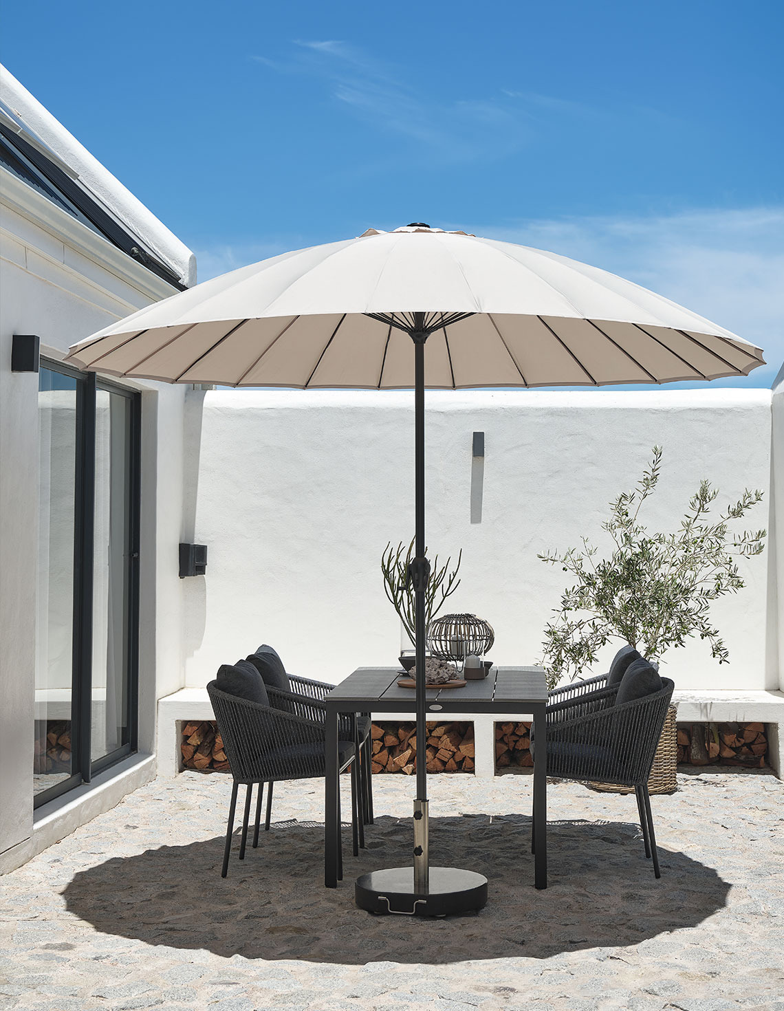 parasol LAMMEHAVE Parasol de jardin beige classique sur une terrasse avec table et chaises de jardin.