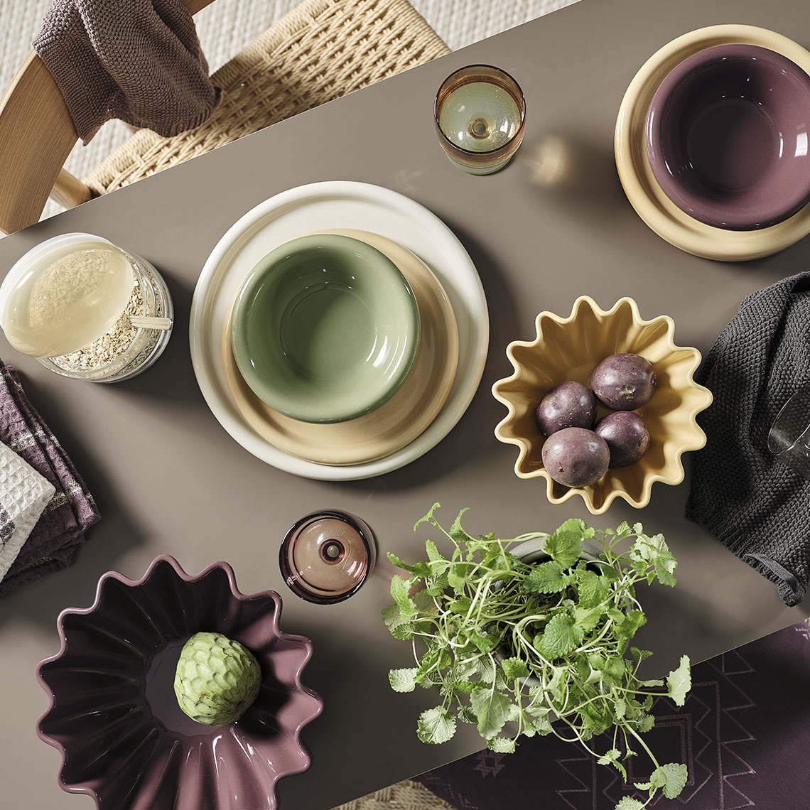 Service de couverts GREGERS, assiettes et bols MALIK, verre ISAK, torchon TISTEL, bocal de conservation DAHL, bols NOR, torchon BARLIND Des bols et des assiettes colorés sur une table à manger