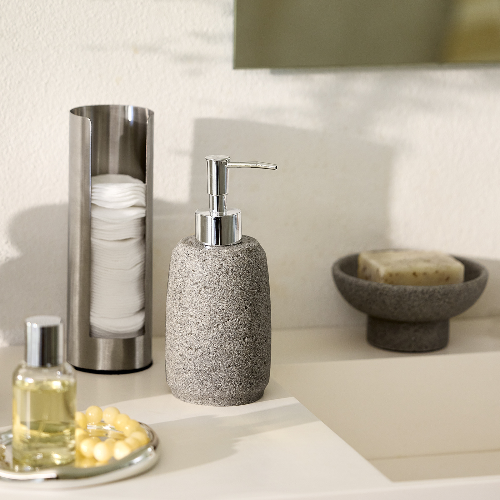 Distributeur de savon, coupelle décorative et porte-cotons près d’un lavabo