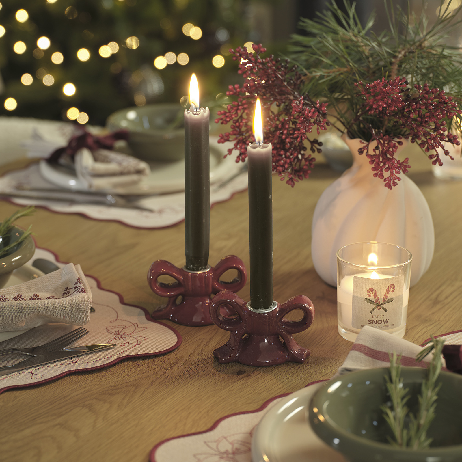 Table de Noël décorée d’un vase avec des fleurs artificielles et de bougeoirs avec des bougies