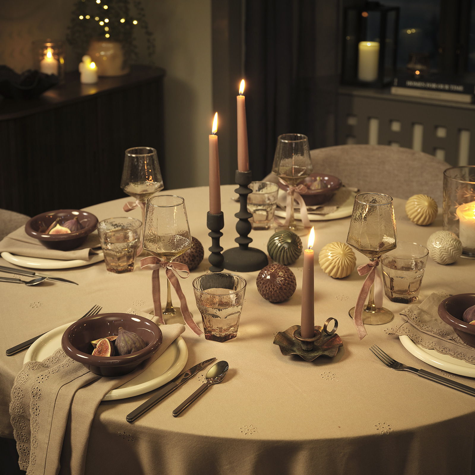 Table de fête éclairée à la bougie avec des assiettes, des bols, des couverts et des décorations